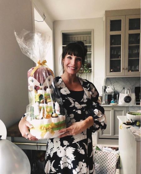Alida Morberg carrying a huge cake wrapped in plastic.