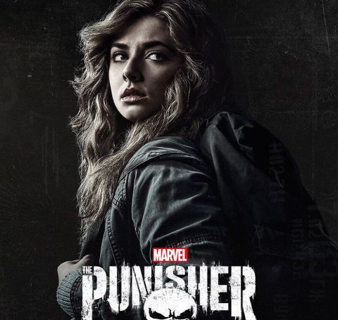 Giorgia Whigham, all in black looks behind in The Punisher's wallpaper.