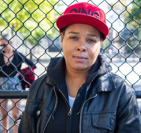 Chaunte Wayans in a black leather jacket and a red cap. 