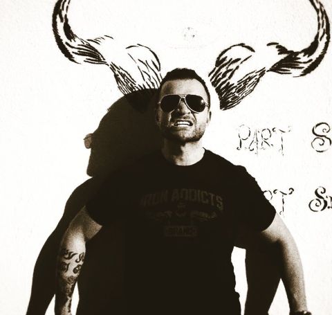 Nick E. Tarabay posing in front of camera in a black t-shirt and black spectacles. 