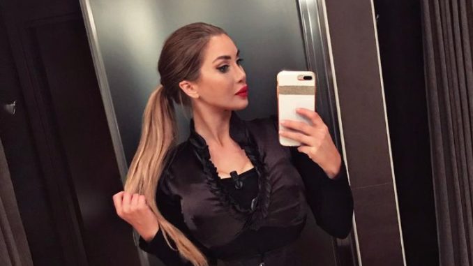 Pixee Fox in a beautiful black dress clicks a mirror selfie holding her highlighted hair.