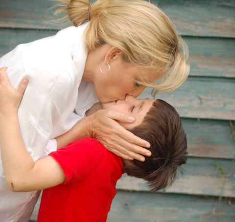 Sylvia Jefferies in white shirt kissing her child in red tshirt.