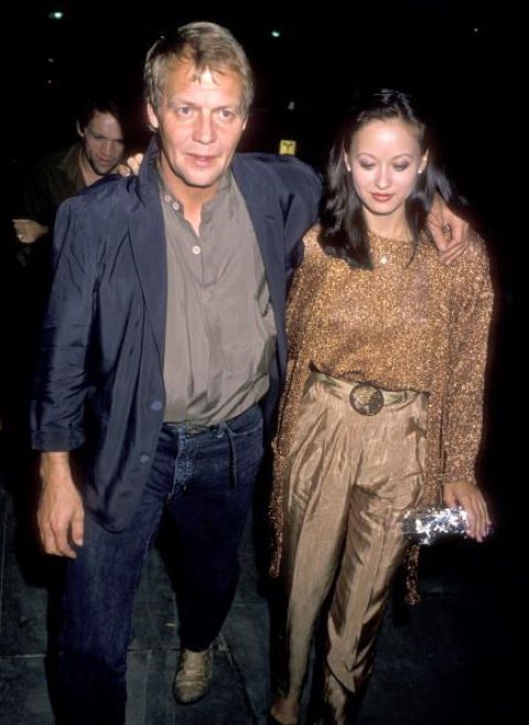 Julia wearing a brown pant, blouse and jacket is with her ex-husband David wearing a blue suit at a party.