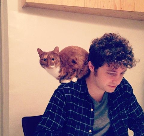 Kyle Soller in a black shirt with cat on his shoulders. 
