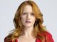 Paula Malcomson with auburn hair and blue eyes wearing a red dress.