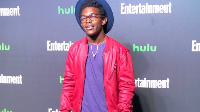 Camrus Johnson in a red jacket and blue t-shirt at a Hulu event.