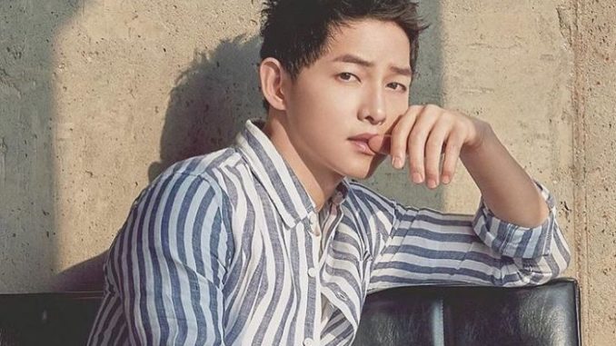 Song Joong-ki posing for a picture in a black-white shirt.