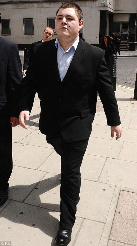 Jamie Waylett walking in street while wearing a black tuxedo.