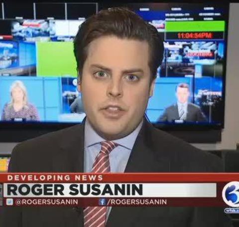 Roger Susanin in a black tux reporting a news on live television.