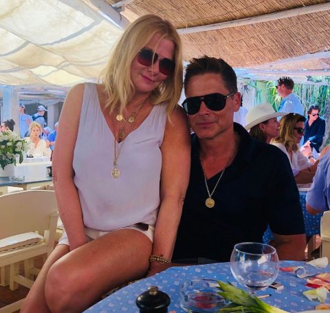 Sheryl Berkoff in white sitting in the lap of husband Rob Lowe.