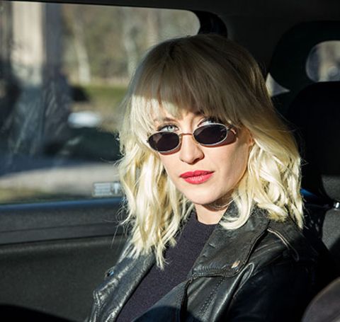 Julia Ragnarsson in a black leather jacket poses in the car. 