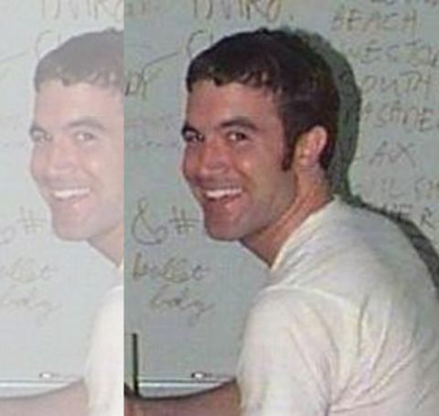 Tom Anderson in a white t-shirt poses for a picture.