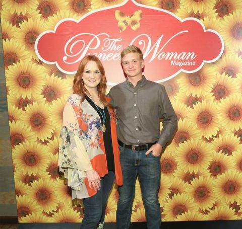 Bryce Drummond in grey shirt poses with famous mom Ree Drummond in The Pioneer Woman sets.