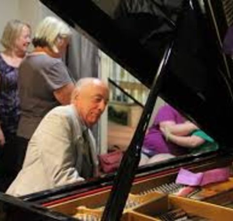 John Towey in a grey coat playing the piano.