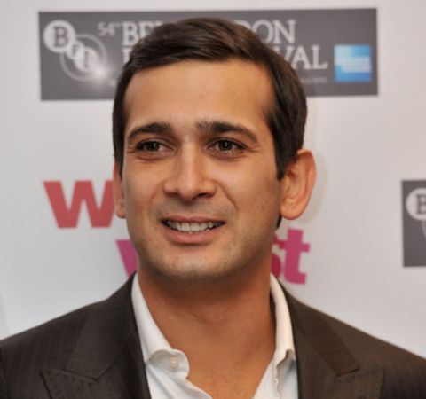 Jimi Mistry in a black suit poses for a photoshoot at an event.