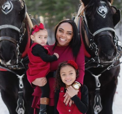 Shayanna  Jenkins in red dress poses with her two daughters.