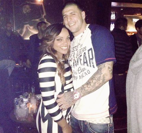 Shayanna  Jenkins in a black an white dress poses alongside NFL star Aaron Hernandez in a club.