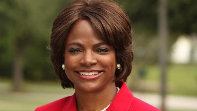 Val Demings in a red coat poses for a picture.