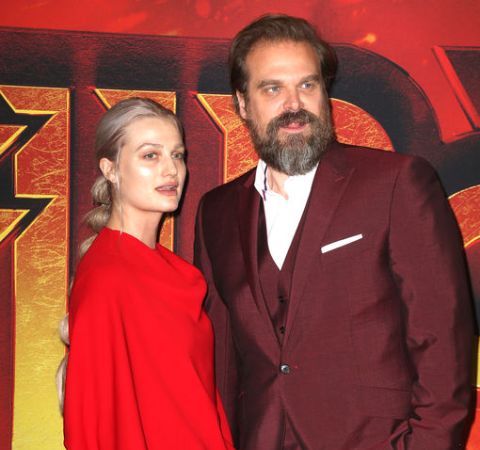 Alison Sudol in a red dress poses alongside the multi-talented David Harbour.