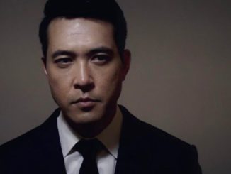 Jonathan Ohye in a black suit poses for a photoshoot.