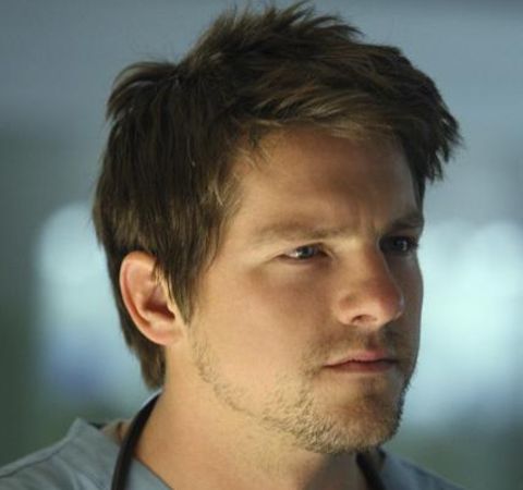 Zachary Knighton in a grey shirt poses for a picture.