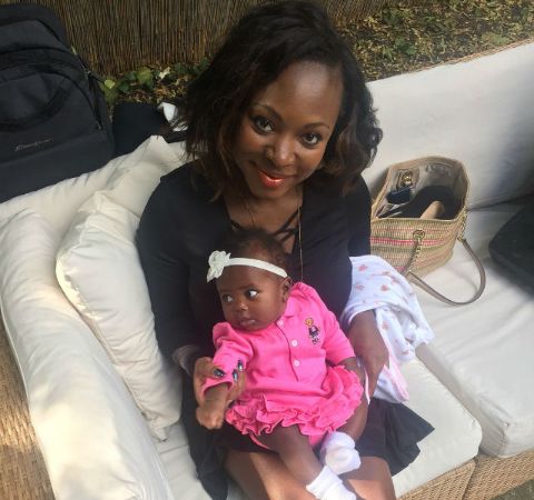 Naturi Naughton in a black dress poses with her baby  daughter in pink.