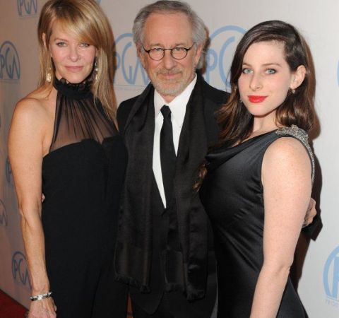 Sasha Spielberg in a black dress at right poses with her dad Steven Spielberg.