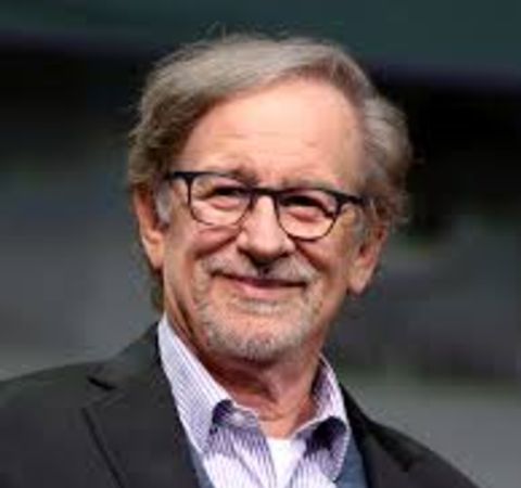 Steven Spielberg in a black suit  poses for a picture.