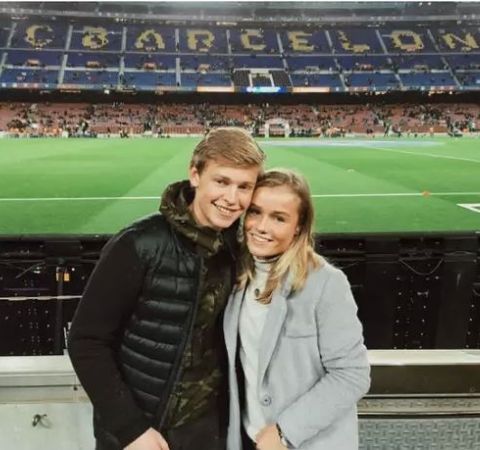 Mikky Kiemeney in a black white coat poses with De Jong at Camp Nou.