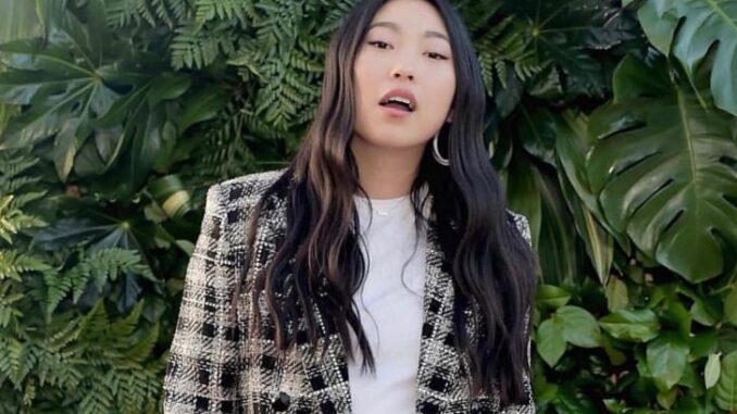 Awkwafina posing for a picture in a white t shirt and a checked outer