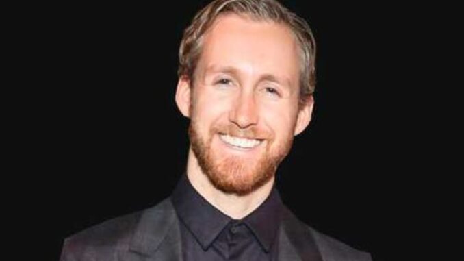 Adam Shulman wearing a black suit and smiling