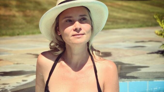 Kristina Klebe wearing a black swimsuit and hat and posing for a photo.
