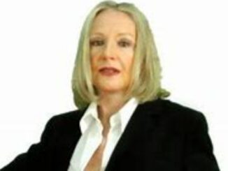 Alexandra Lorex wearing a black suit and white t-shirt and posing for a photo.