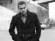 O. T. Fagbenle wearing a black overcoat and posing for a photo.